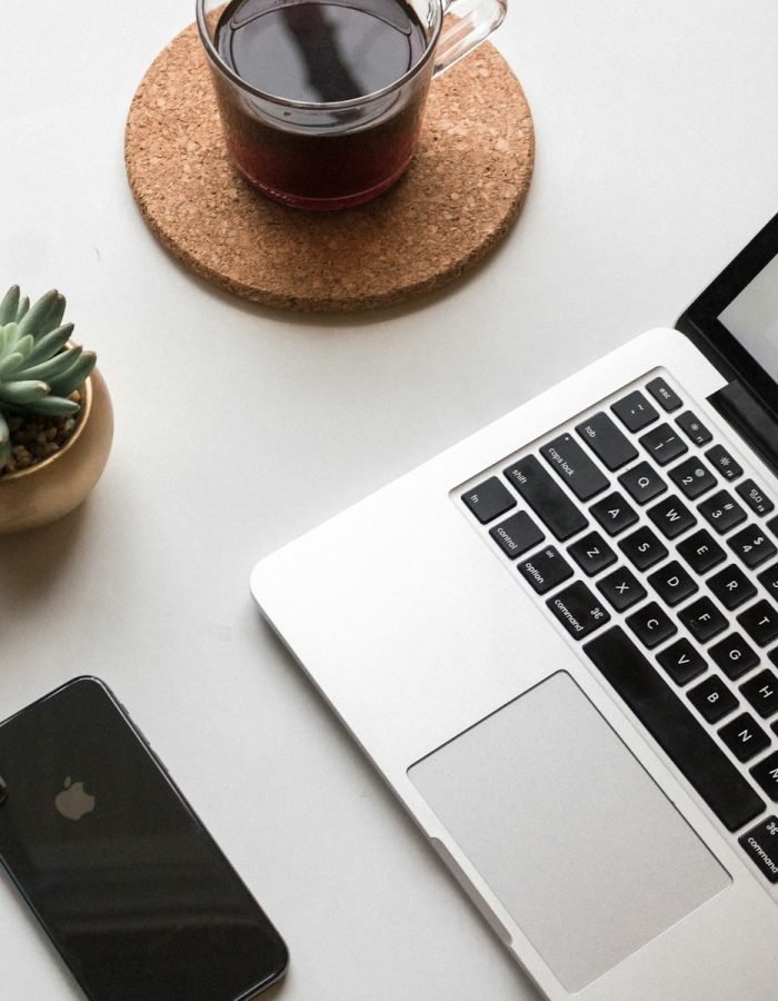 space gray iPhone X beside turned on laptop beside coffee and succulent plant